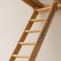 A wooden loft ladder extending from a ceiling in a neutral-toned room, illustrating safety in home access solutions.